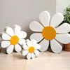 Set of three white and orange wooden daisy flower ornaments displayed on a light wood surface.