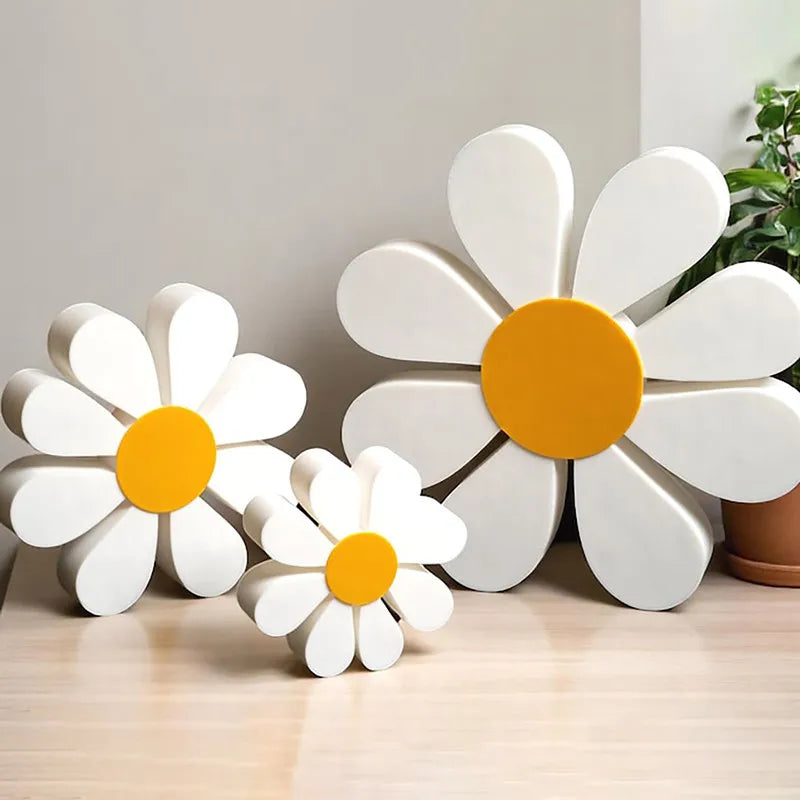 Set of three white and orange wooden daisy flower ornaments displayed on a light wood surface.