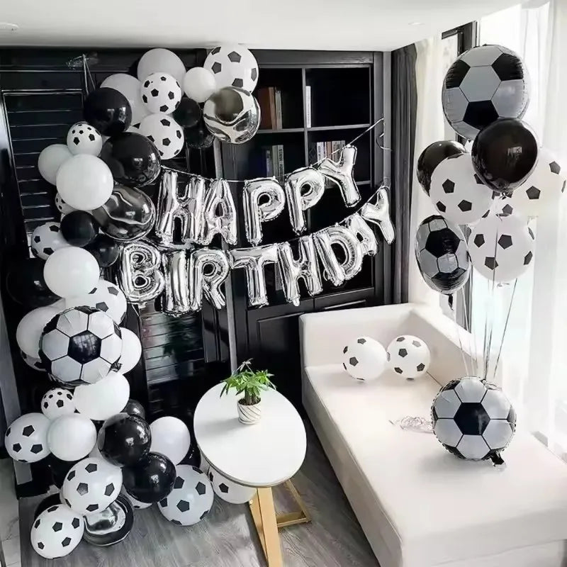 A large arrangement of black and white latex football shaped balloons for a birthday party decoration.