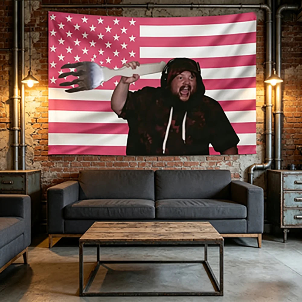 Eine Person mit Hoodie hält eine große Hand vor ein rosa-weißes amerikanisches Flaggen-Tapestry in einem rustikalen Innenraum