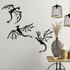 A set of three black dragon metal wall art panels hanging on a white wall next to decorative light fixtures.