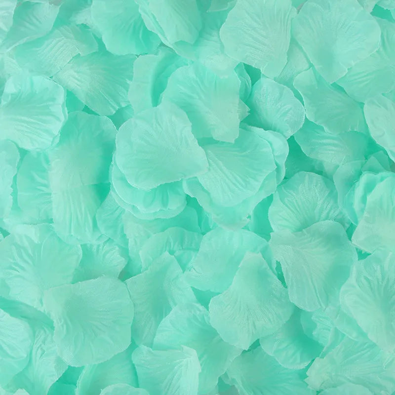 Light mint green silk rose petals scattered on a surface for decor