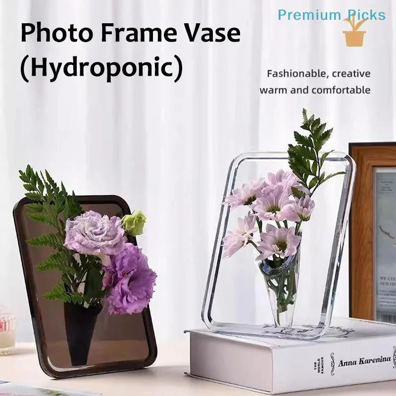 A clear acrylic photo frame vase holding purple flowers and greenery.