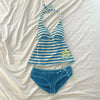 A blue and white striped sleeveless top with a yellow graphic detail laid out on a white surface, along with matching blue bo