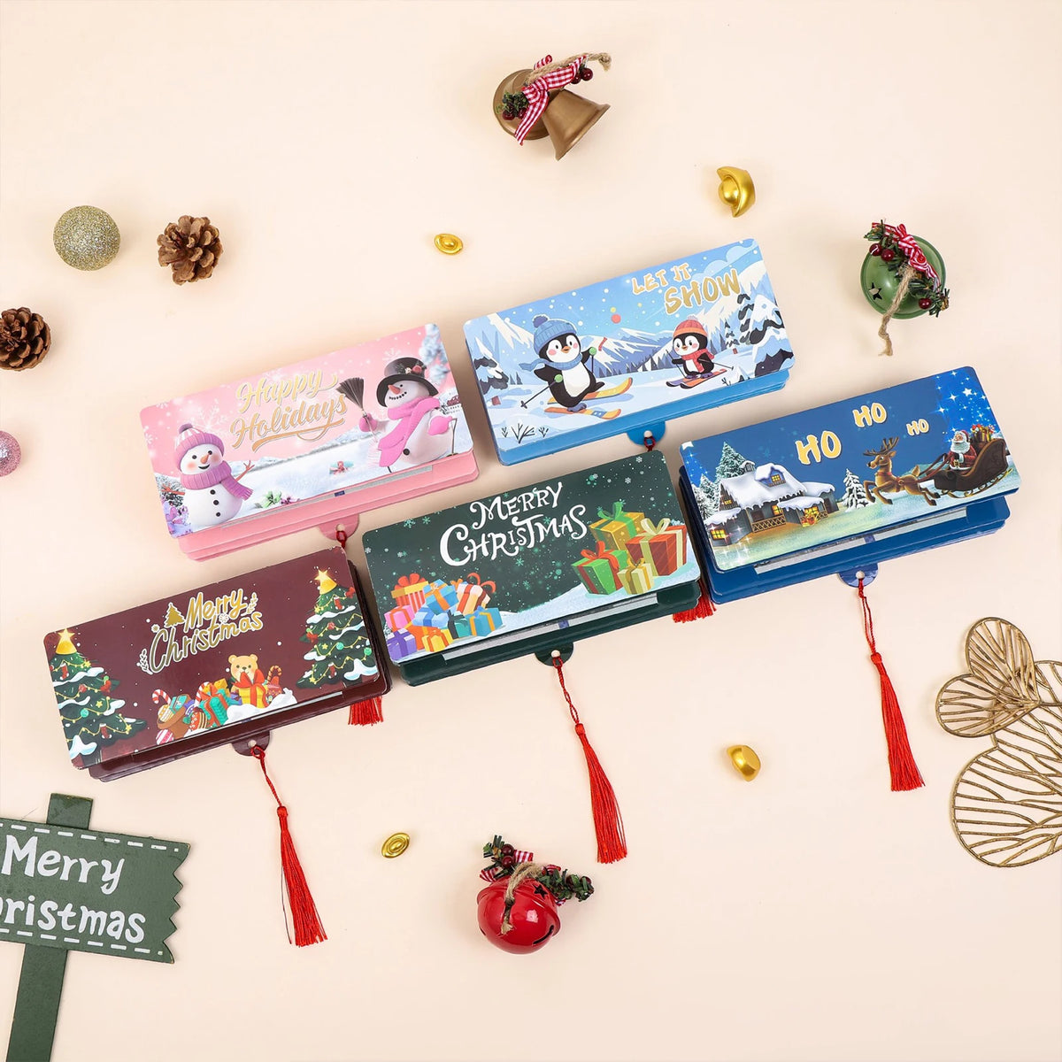 A collection of festive cash gift boxes and decorative items, including a pink holiday box and blue snow scene boxes.