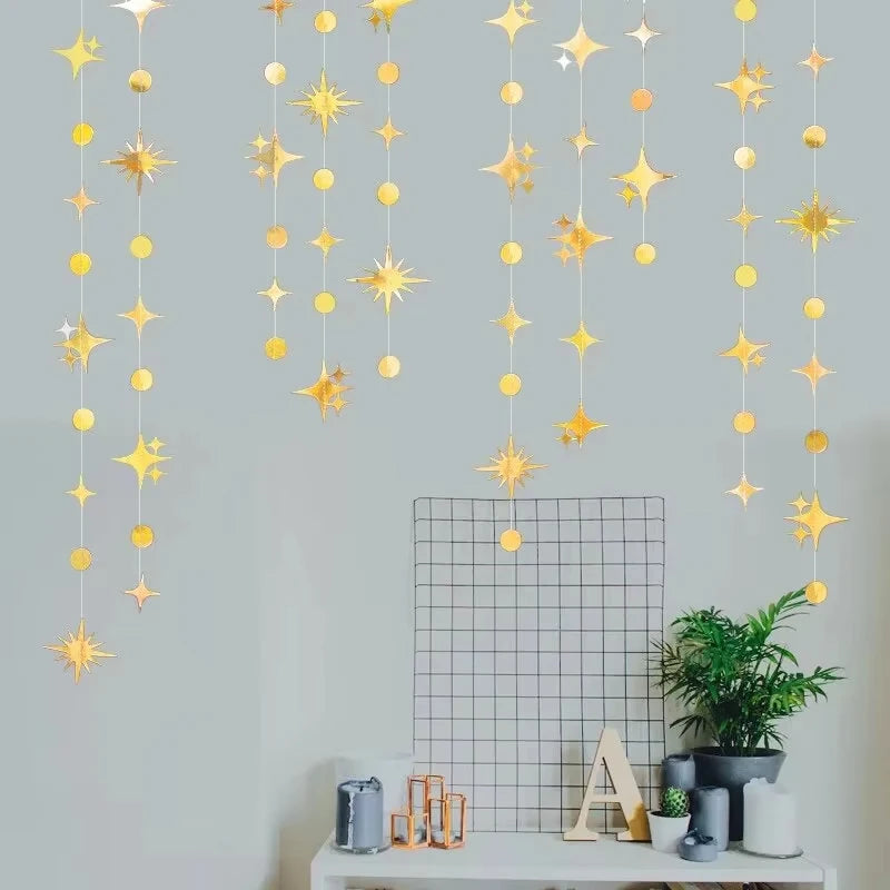 A vertical display of a glittering gold star and polka dot garland kit hanging against a light gray wall.