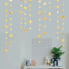 A vertical display of a glittering gold star and polka dot garland kit hanging against a light gray wall.