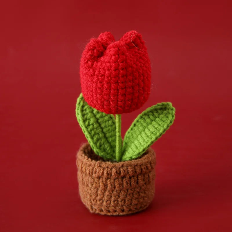 Handcrafted red crochet tulip flower growing in a brown crocheted pot.