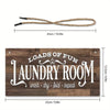 A wooden sign with the text LOADS OF FUN LAUNDRY ROOM wash dry fold repeat and a rope for hanging