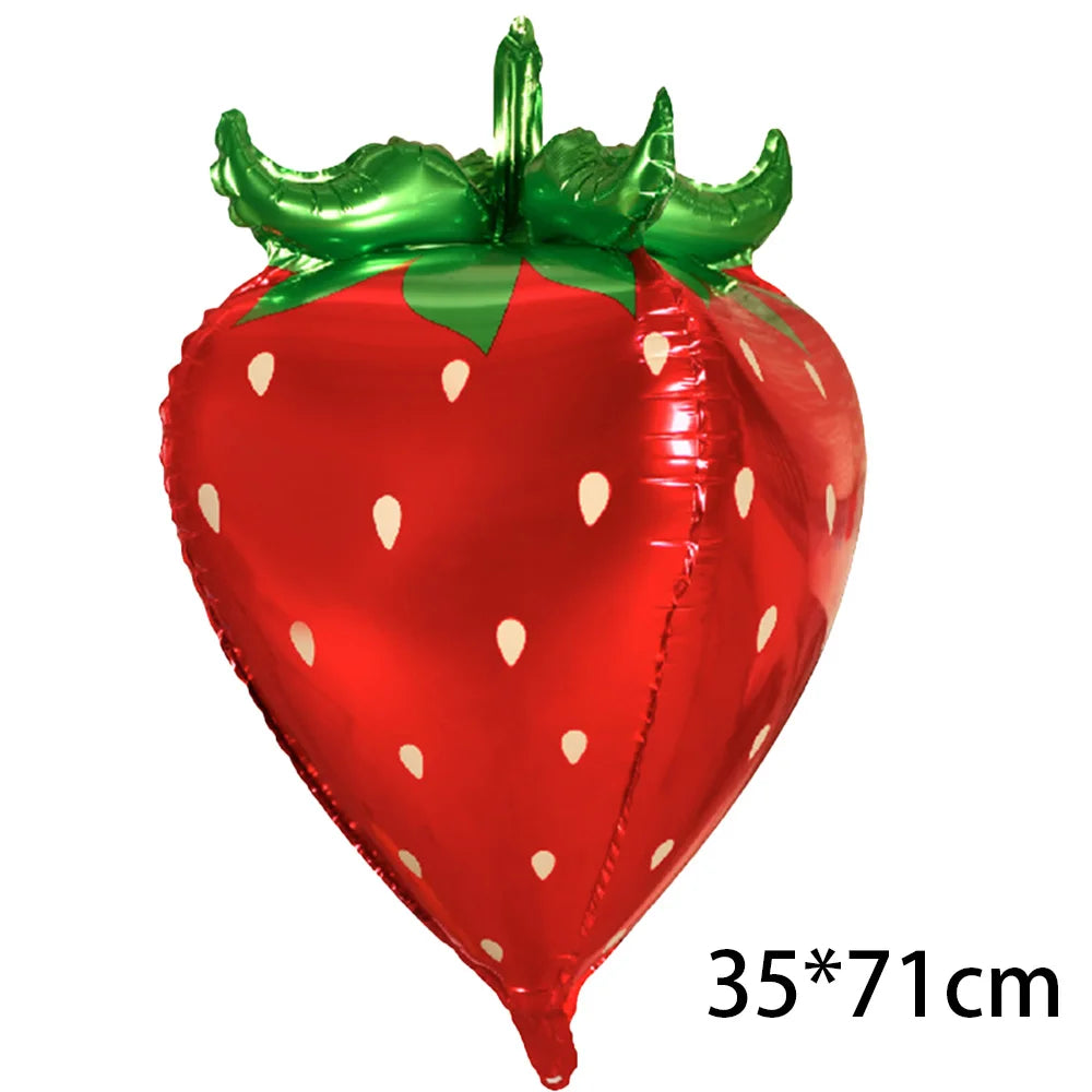 A shiny red inflatable strawberry with green leaves, used as a party decoration.