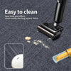 A close-up of a black artificial grass carpet cleaning tool with a yellow cleaning pad on a dark gray textured surface.