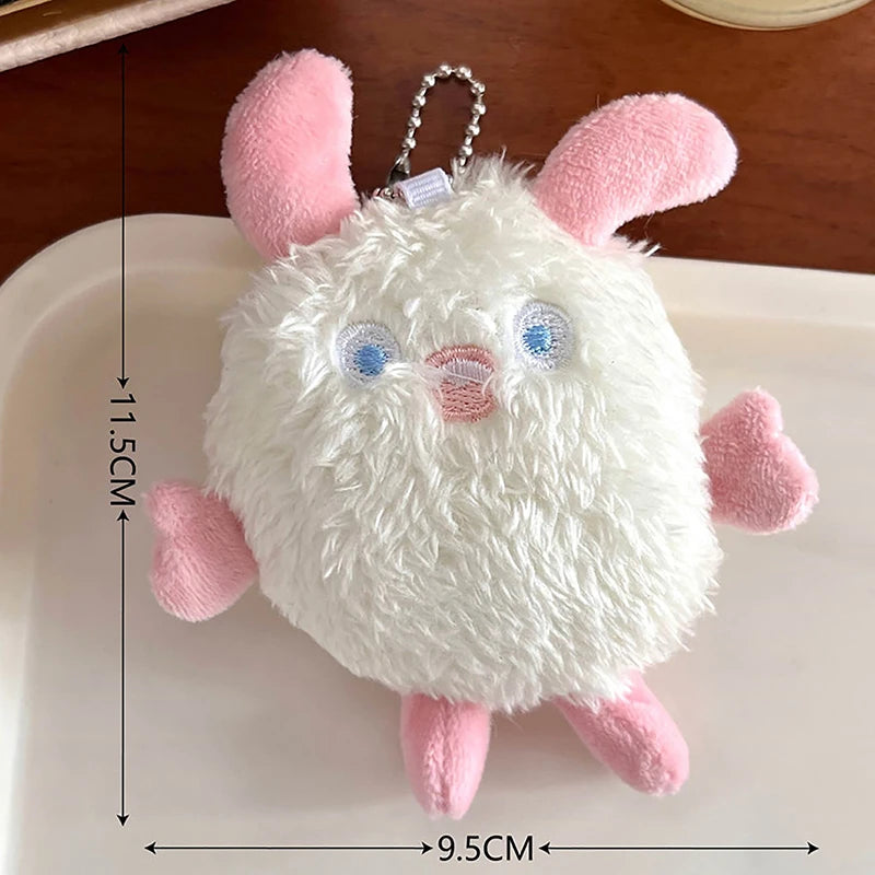 A white fuzzy plush monster with pink ears and feet is shown on a white surface.