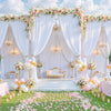A white fabric backdrop curtain decorated with pink and white flowers and draped fabric for an event.