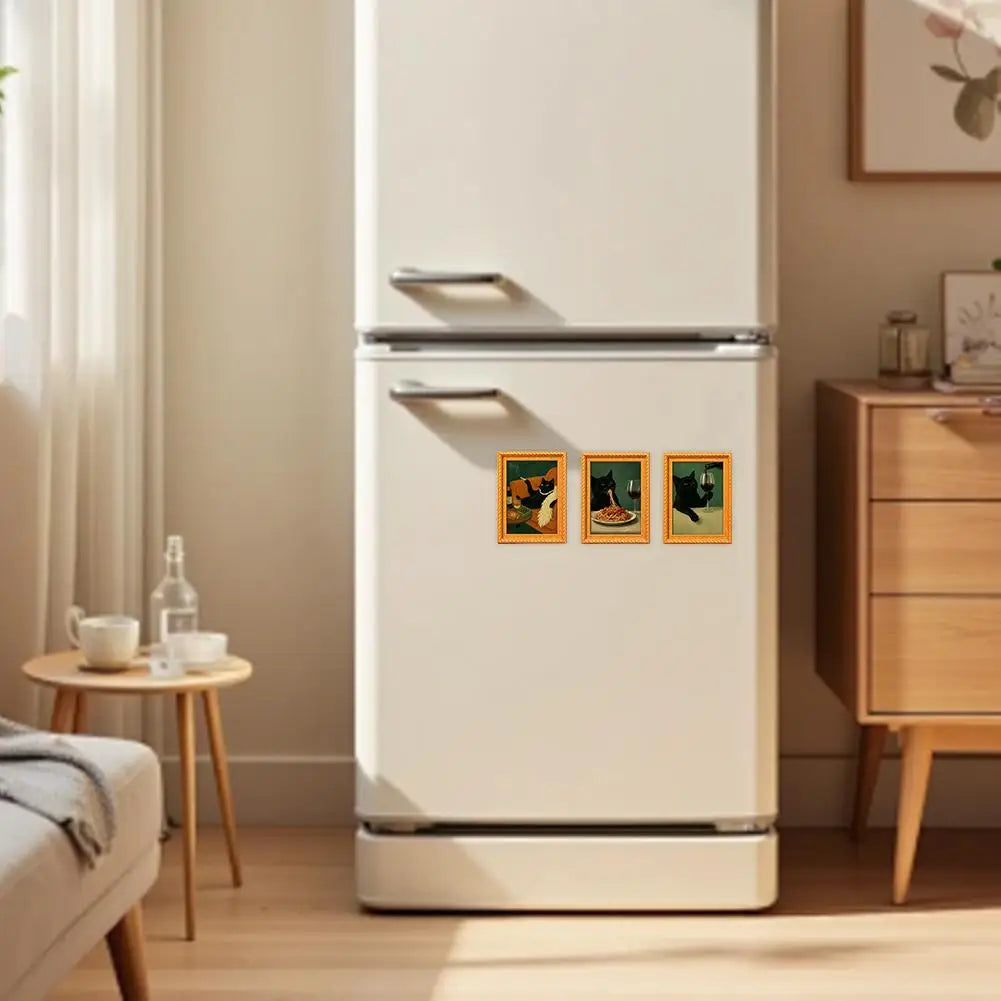 A white refrigerator features three vintage style wooden magnets depicting playful black cat art.