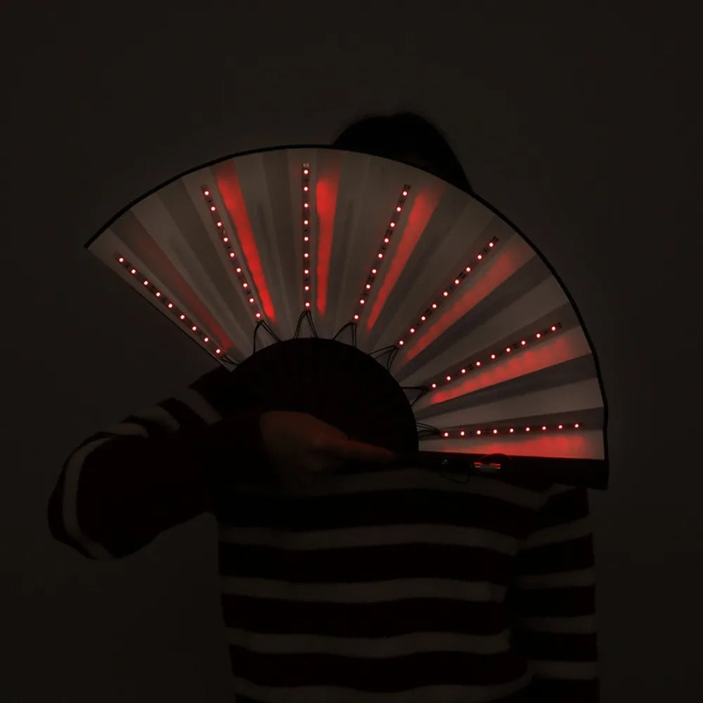 شخص يمسك مروحة إضاءة حرير LED قابلة للطي، تصدر أشعة ضوء حمراء.