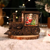 A rustic wooden Christmas train music box with LED lights and a water-filled crystal ball sits on a wooden surface.