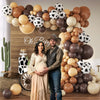 Una pareja posando frente a una gran instalación de globos con tonos tierra y globos blanco y negro.