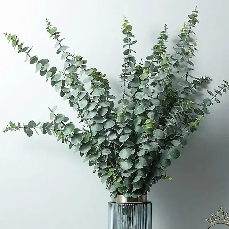 A bouquet of artificial eucalyptus stems with realistic green leaves displayed in a metallic vase.