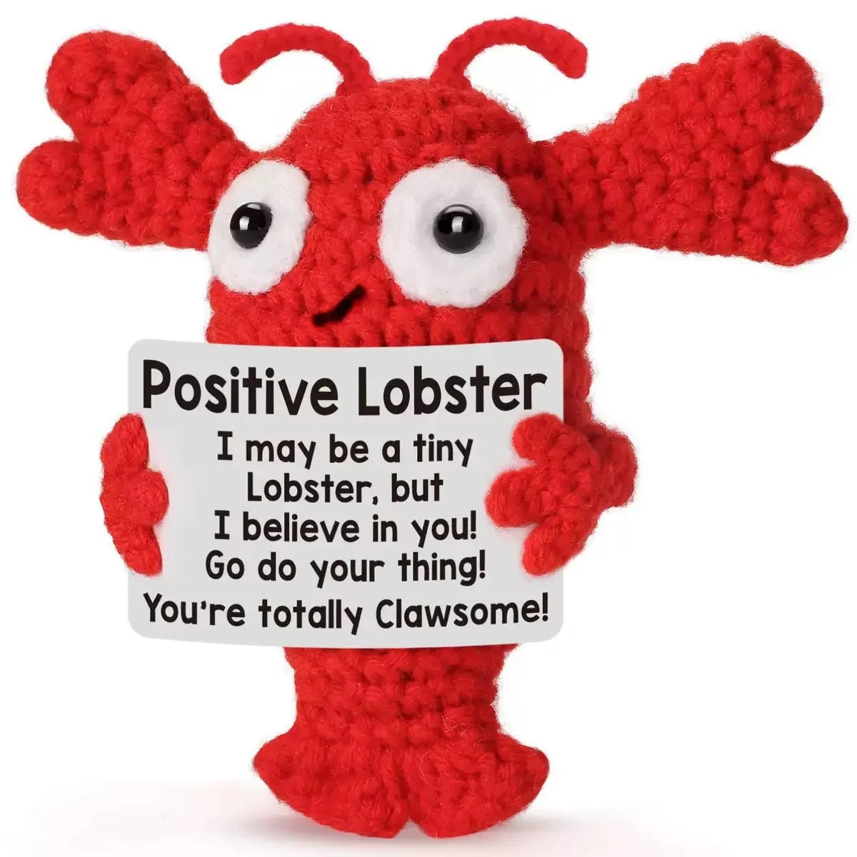 A handmade red crochet lobster doll with large eyes and an inspirational card attached.