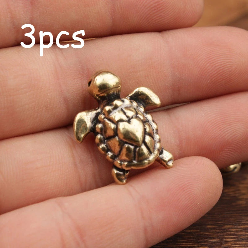 Three brass handcrafted turtle figurines held in a person's hand.