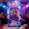 A colorful K-Pop themed photo frame backdrop for a birthday party with people celebrating in the background.