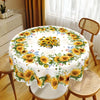 A white tablecloth with a yellow and green sunflower print is displayed on a round table in a bright room.