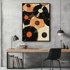 A framed canvas art print featuring a collection of black and orange vinyl records hanging on a gray wall above a wooden desk