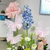 Pink and blue silk artificial butterfly decorations arranged with flowers.