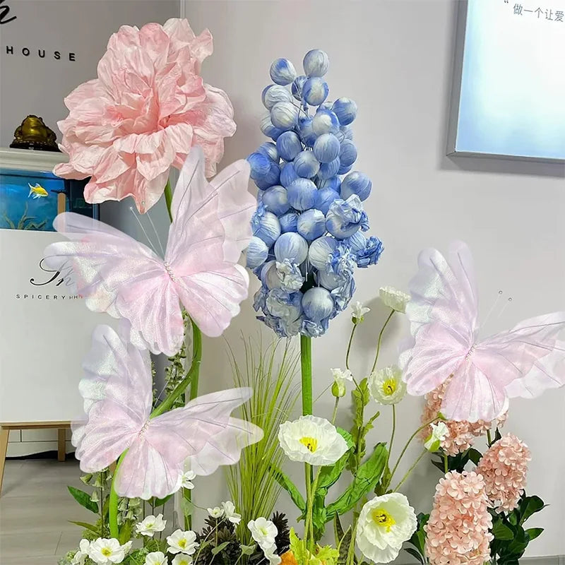 Pink and blue silk artificial butterfly decorations arranged with flowers.