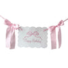 Pink decorative birthday garland with white icing-like cutouts and pink ribbons