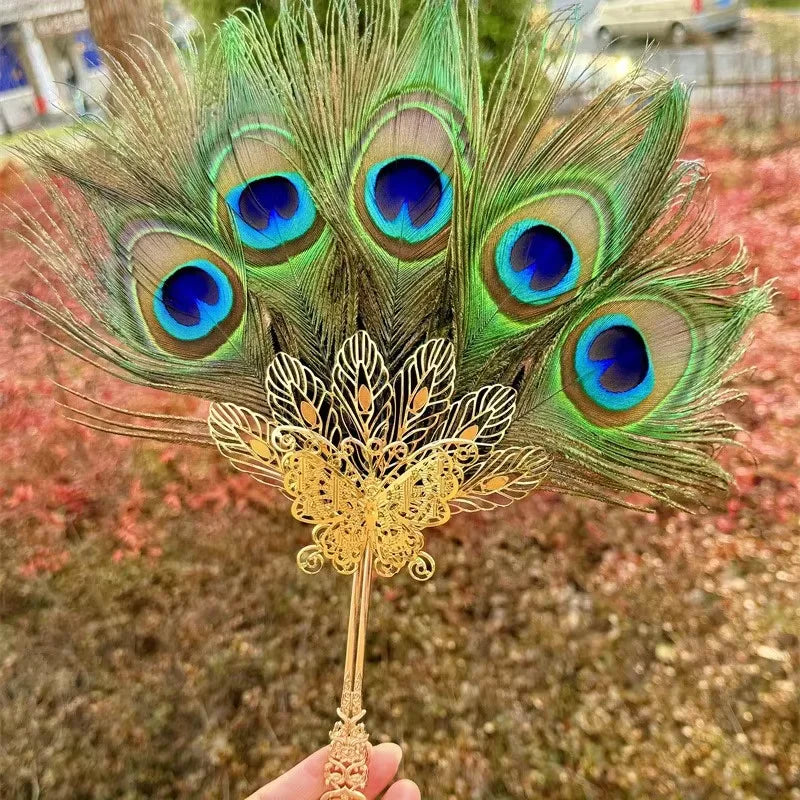 Plume de paon naturelle utilisée comme éventail, avec des plumes vertes et bleues vibrantes.