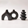 A set of three matte black ceramic vases with organic, sculptural shapes.