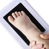 A handprint and footprint memory kit showing a baby's foot being placed inside a photo frame.