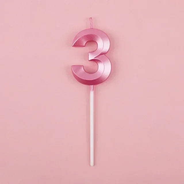 A pink number three candle with a thin stick against a light pink background.