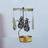 A gold rotating candle holder with a spinning carousel featuring silhouette cutouts of trees and other figures.