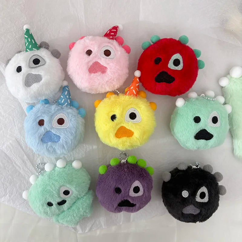 A collection of colorful kawaii plush keychains with various shapes and horns resting on white paper.