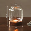 Vintage wooden candle lantern with a glass cover glowing warmly on a wooden surface.