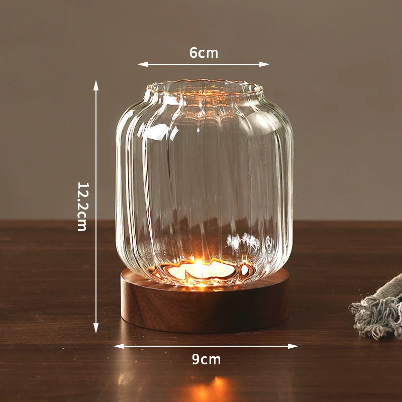 Vintage wooden candle lantern with a glass cover glowing warmly on a wooden surface.