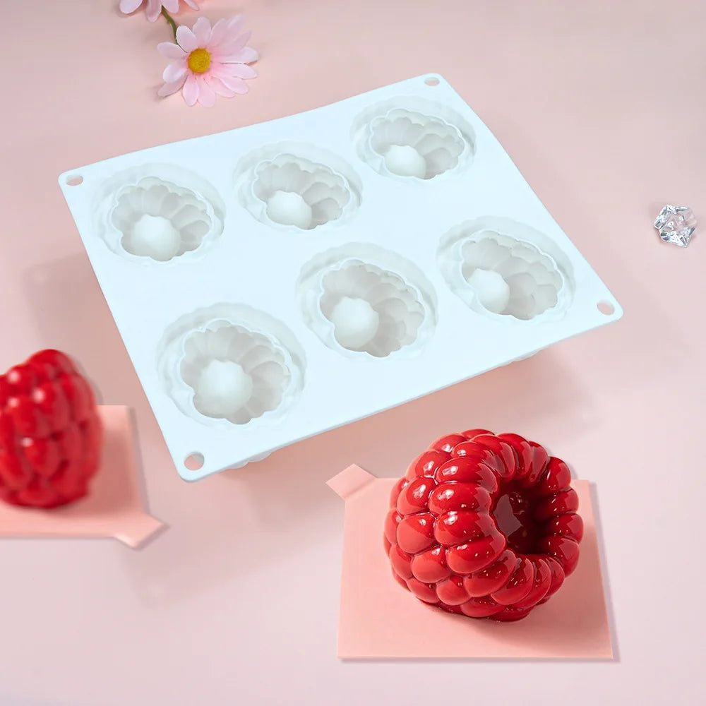 A white silicone mold with six cavities is shown alongside fresh red raspberries.