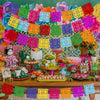 A colorful display of felt papel picado banners in various bright colors strung across a festive background.