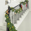 A realistic Norfolk Pine Christmas garland with optional lights draped along a black staircase railing.