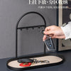A black wrought iron key holder and desk organizer rack with a leather key holder placed on a dark surface.