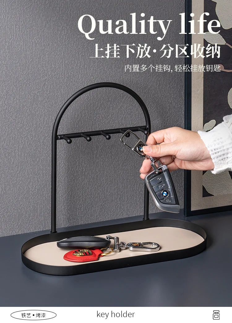 A black wrought iron key holder and desk organizer rack with a leather key holder placed on a dark surface.