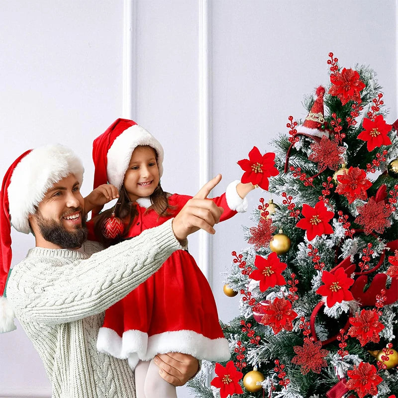 A man and a girl in festive attire are holding a decorated Christmas tree with red flowers.