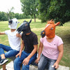 Three people wearing realistic horror animal masks, including a white, black, and orange mask, posing outdoors.