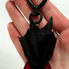 A hand holds a plush black bat keychain with red accents, showing the detail of the transformable gothic bat key ring.