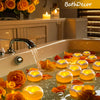 A bathtub filled with water and floating orange and yellow candles in a bathroom setting.