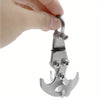 A hand is holding a heavy duty stainless steel gravity hook multi-tool with a curved hook shape.