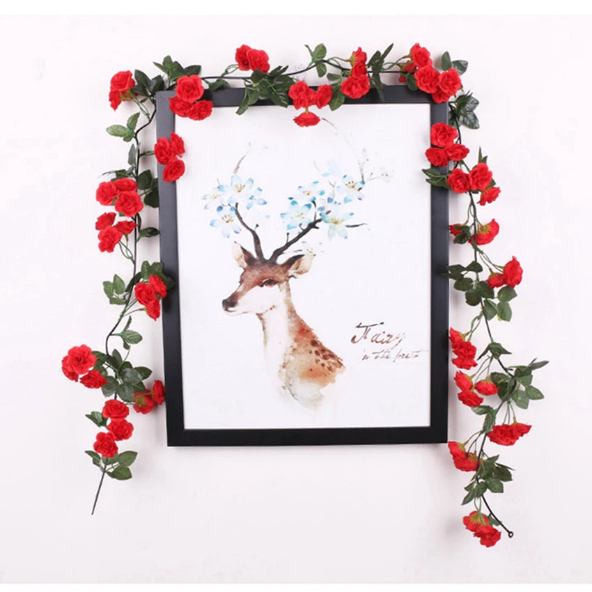 A framed artwork featuring a deer silhouette and blue flowers surrounded by a vibrant red silk rose vine garland.