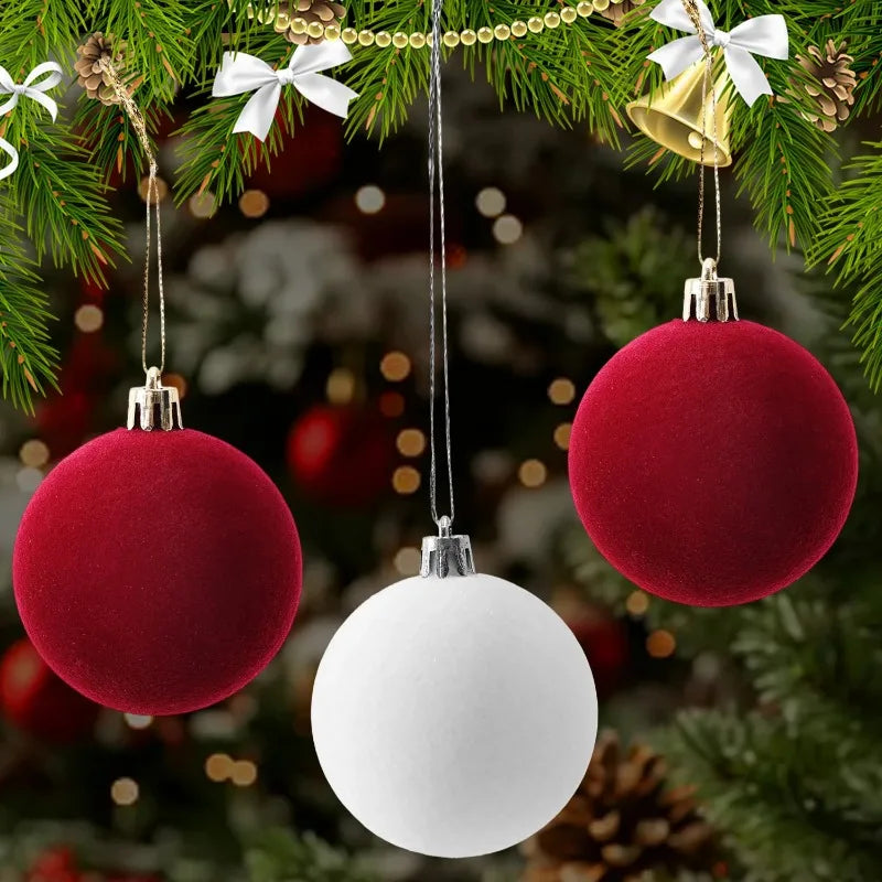 Three velvet flocked Christmas ornaments in red and white hanging on a green pine branch.
